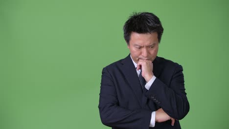 mature japanese businessman against green background