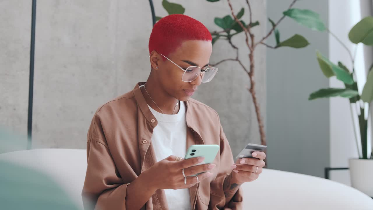 Young african american woman holding credit card and using mobile phone