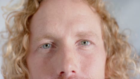 Close-up-of-portrait-of-happy-caucasian-male-doctor-with-curly-hair,-smiling,-slow-motion