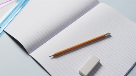 close up of open notebook with school stationery on blue background, in slow motion