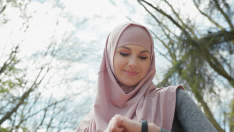 muslim woman checking smartwatch outdoors