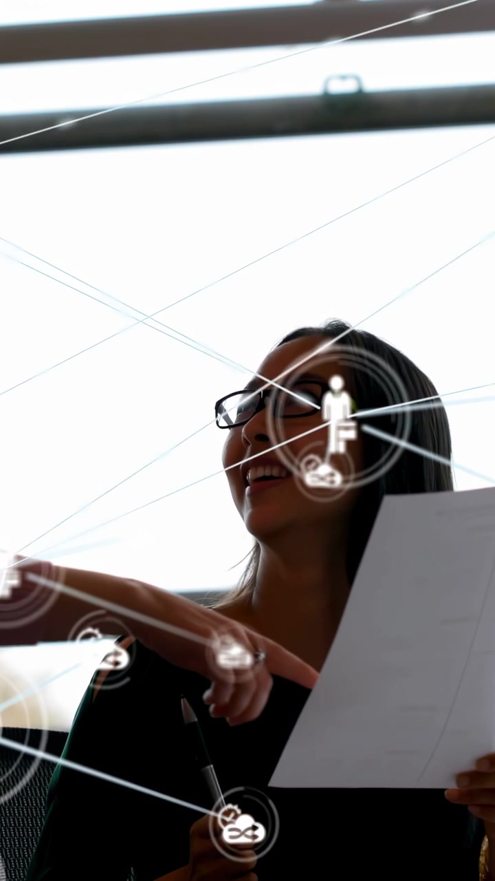 Vertical video: Seated woman with sheet as peer pointing causing network icons for business review