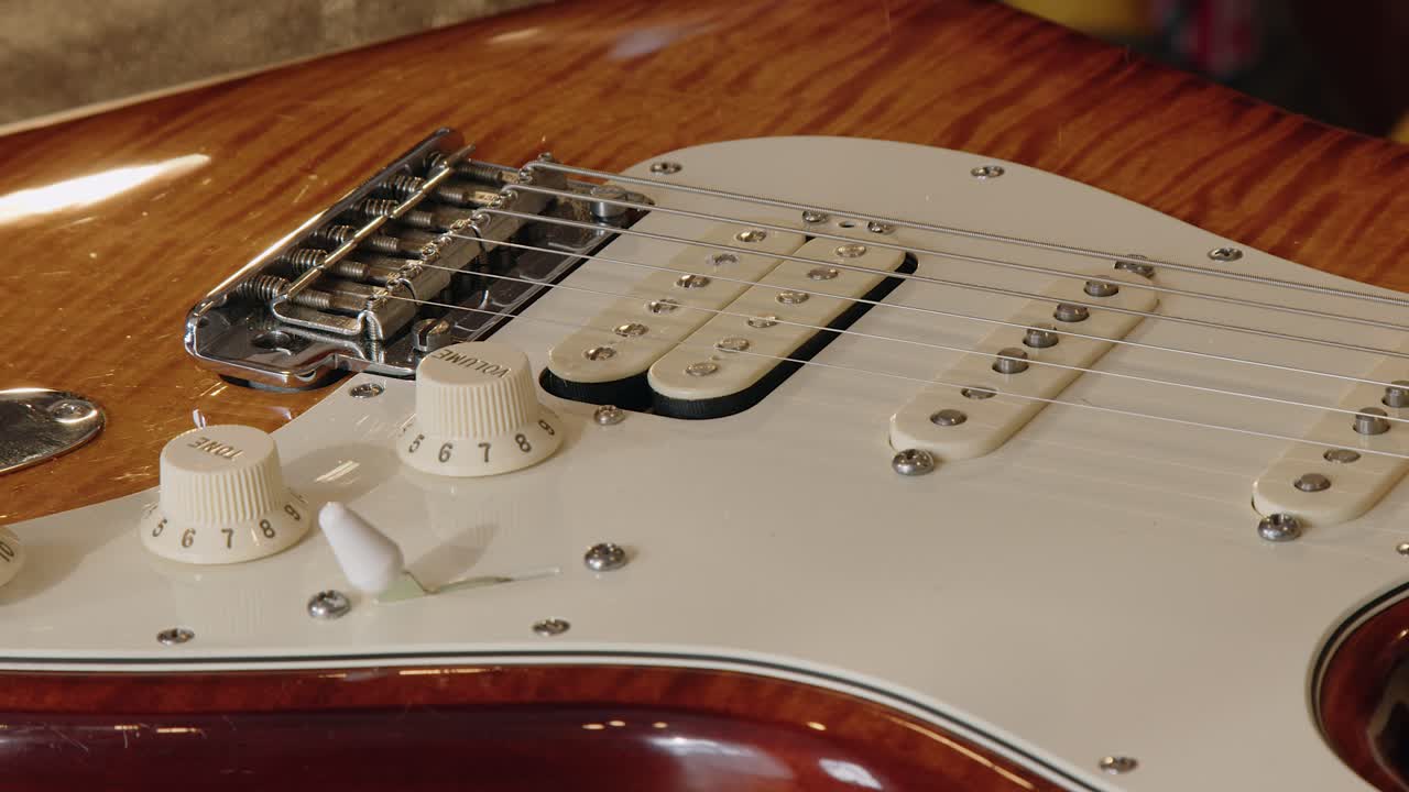 En guitarniker bruger en støvsugerbørste til at rense pickupper på en elektrisk guitar.