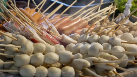 close-up footage of many kinds of steamed skewers displaying at street food market