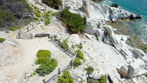 Drone-View-Of-A-Massive-Marble-Wall-In-Aliki-Ancient-Marble-Quarry-With-High-Mountain-Peaks-In-The-Background-And-The-Mediterranean-Sea-In-The-Foreground,-Vivid-Colors,-Thassos-Island,-Greece