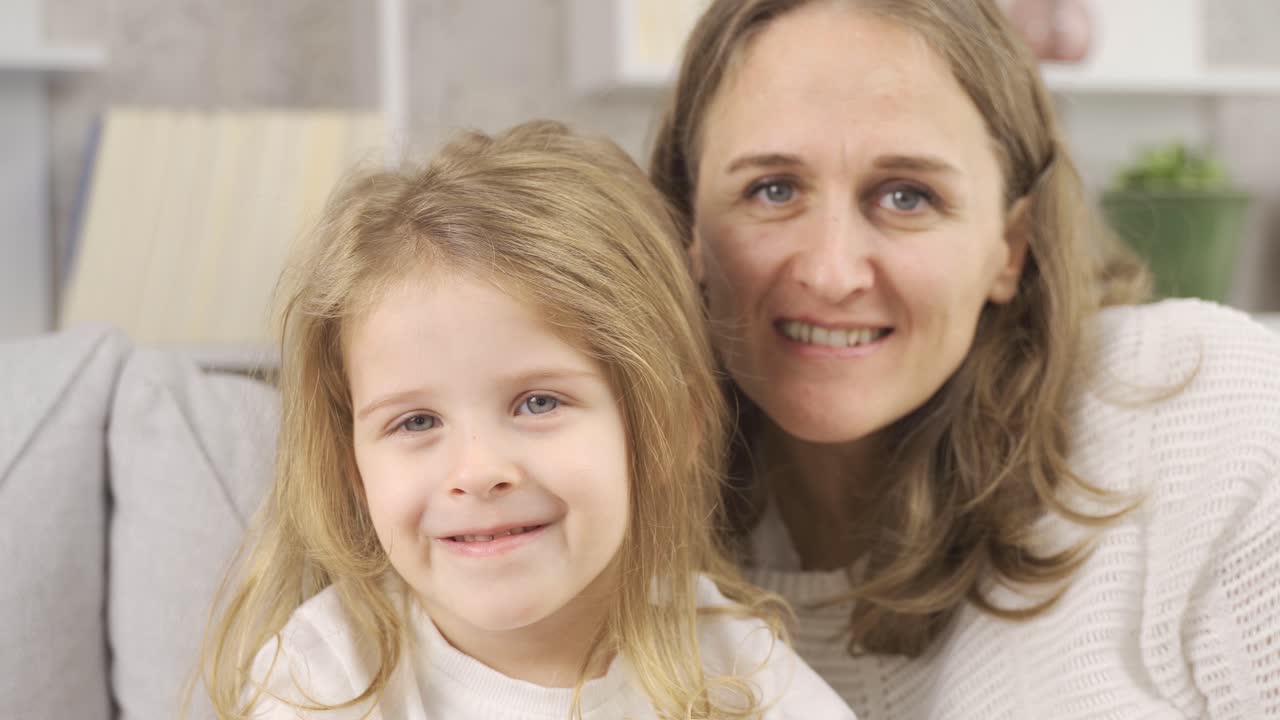 Mutter und Tochter lächeln und schauen in die Kamera.