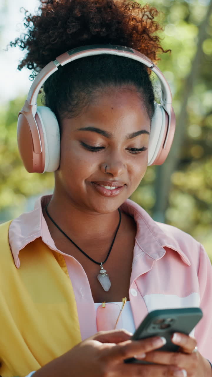 Giovane donna che sorride e ascolta musica in cuffia con lo smartphone.