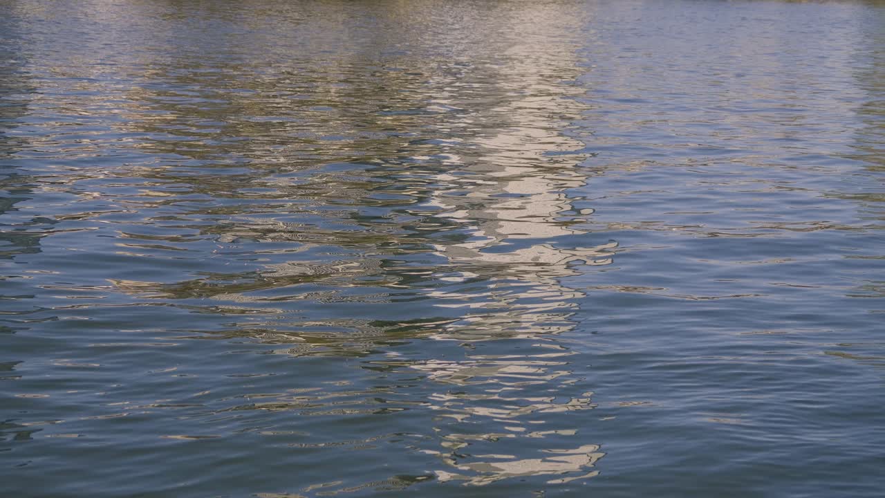 Glittering water surface reflecting the sky and surroundings in gentle waves