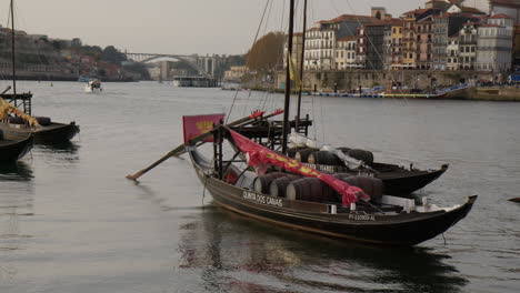 traditional rabelo boats carrying wine barrels at douro river in porto, portugal. wide shot