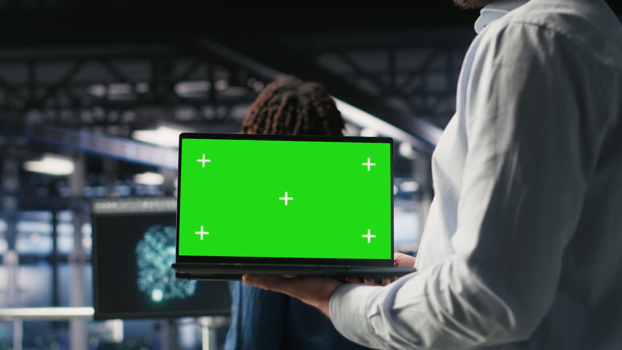 Close up of server room worker using green screen laptop next to colleague