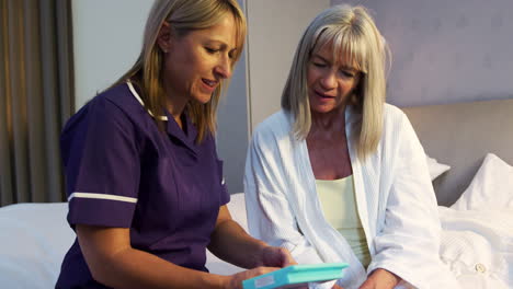 nurse helping senior woman with medication on home visit