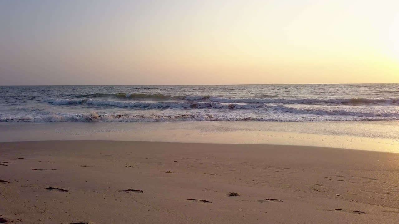 Parallel movement viewing waves crashing on beach during sunset