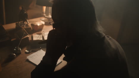Older passionate man evaluates an old watch in his office at night