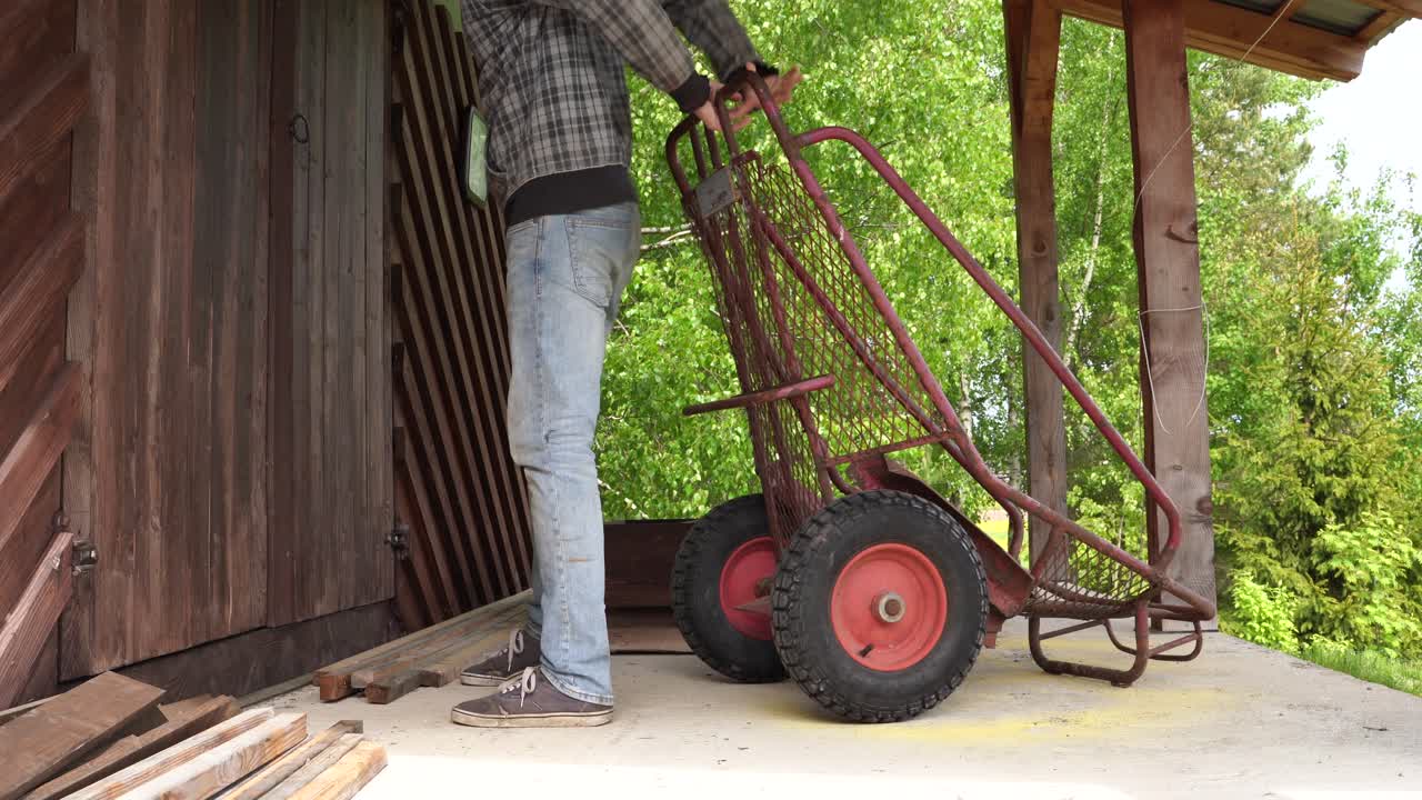 joven poniendo un carro de carga pesada en un cobertizo para leña y cerrándolo