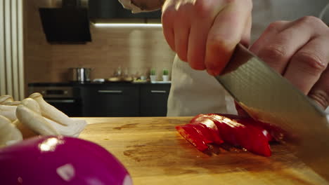 chef slicing red pepper and mushrooms in kitchen