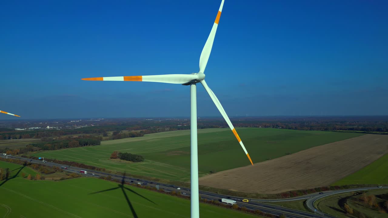 Wind turbine standing in green field next to highway autobahn in autumn Germany, generating renewable energy. Fabulous aerial view flight panorama overview drone