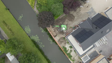 Top-down-aerial-of-excavator-near-new-house---drone-lifting-up-and-spinning