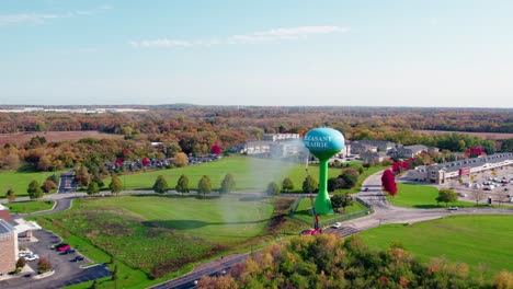 Utility-truck-power-washing-a-water-tower-against-a-suburban-landscape-backdrop,-fall-season-in-Pleasant-Prairie,-Wisconsin,-USA