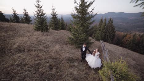 Newlyweds.-Caucasian-groom-with-bride-walking-on-mountain-slope.-Wedding-couple