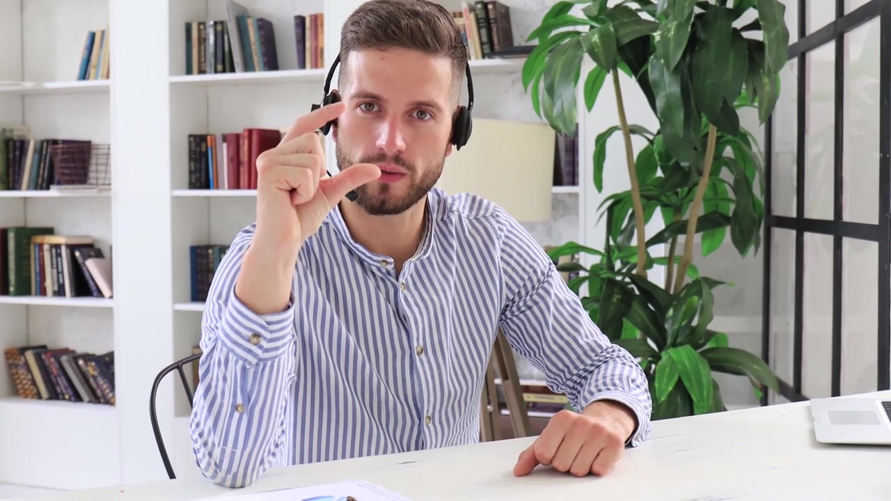 Giovane uomo con auricolare che parla e gesticola durante una videochiamata