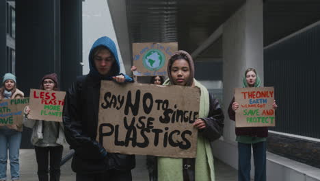 Young-Male-And-American-Female-Activists-Holding-A-Cardboard-Placard-During-A-Climate-Change-Protest-While-Looking-At-Camera