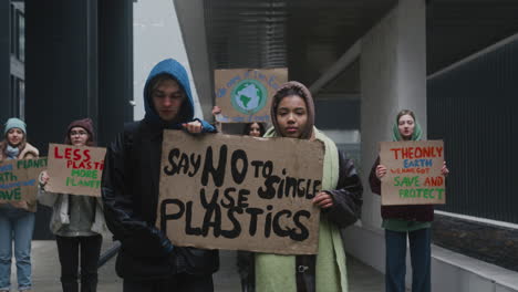 jóvenes activistas masculinas y estadounidenses sosteniendo una pancarta de cartón durante una protesta por el cambio climático mientras miran la cámara