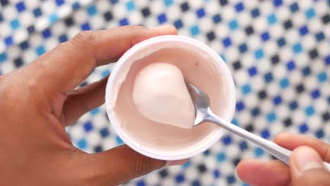 mano sosteniendo un recipiente de yogur con una cuchara
