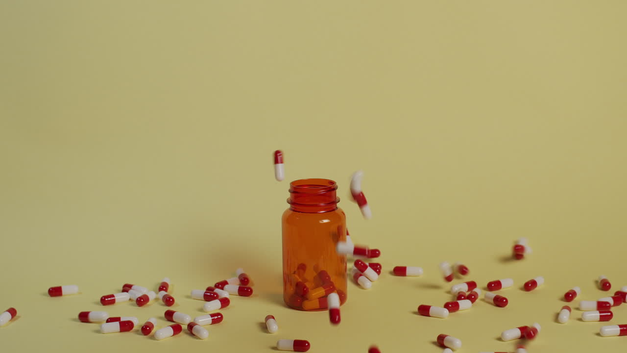 한 줌의 알약이 열린 약병을 향해 떨어질 때 슬로우 모션 와이드 샷