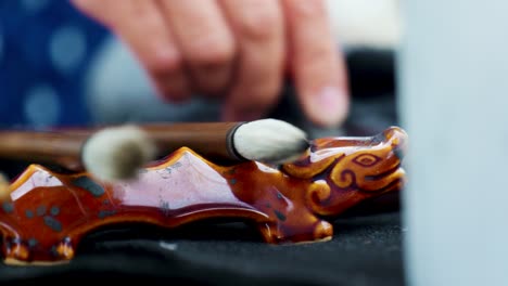 footage of a japanese man making a nihonga, a traditional japanese painting, with brushes and black ink