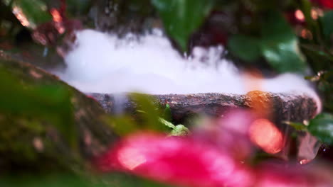 Steaming-and-bubbling-stone-bowl-fountain-in-tropical-garden-rockery