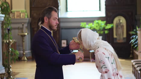 priest blessing parishioner with holy cross