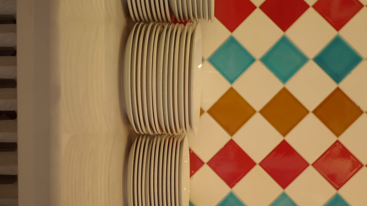 Stacks of Clean White Plates Against a Colorful Tiled Wall