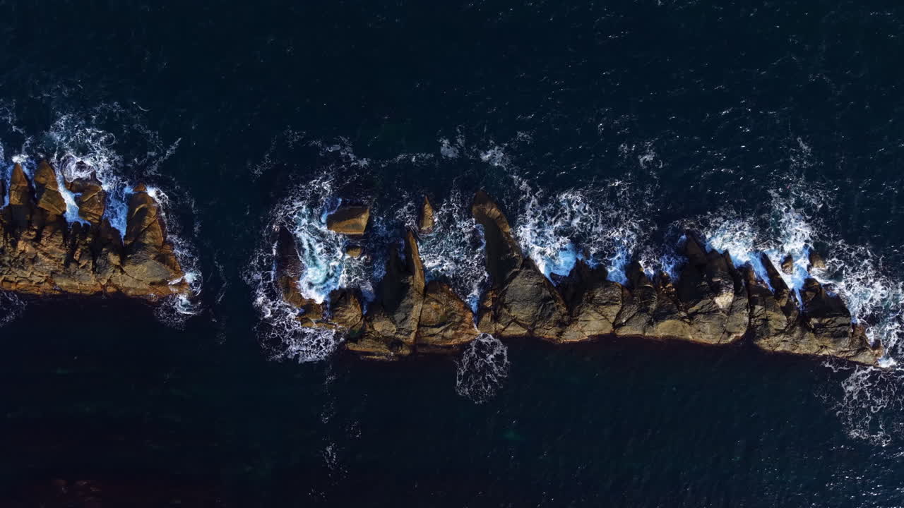 Waves crashing on rugged rocks along the coastline at sunset revealing the beauty of nature s untouched landscape