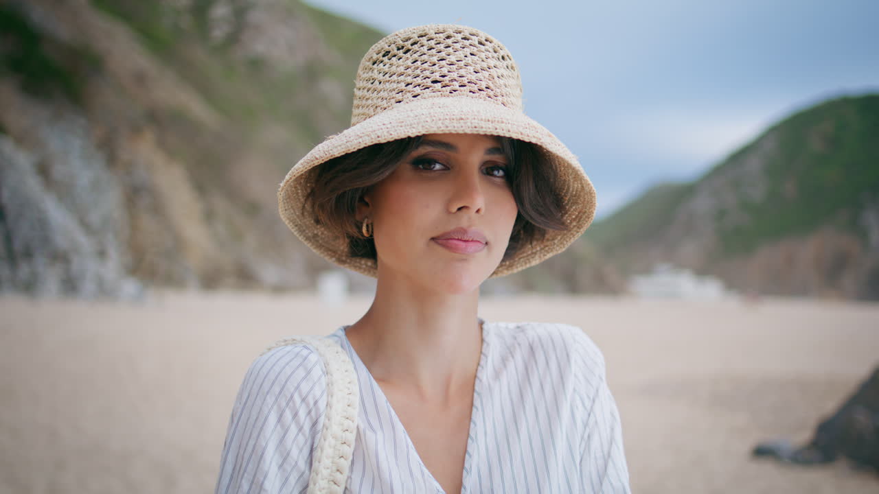 una dama de verano posando en la playa con un sombrero de paja en primer plano. una chica atractiva descansando en la orilla del mar