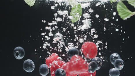 video of berries falling into water with copy space on black background