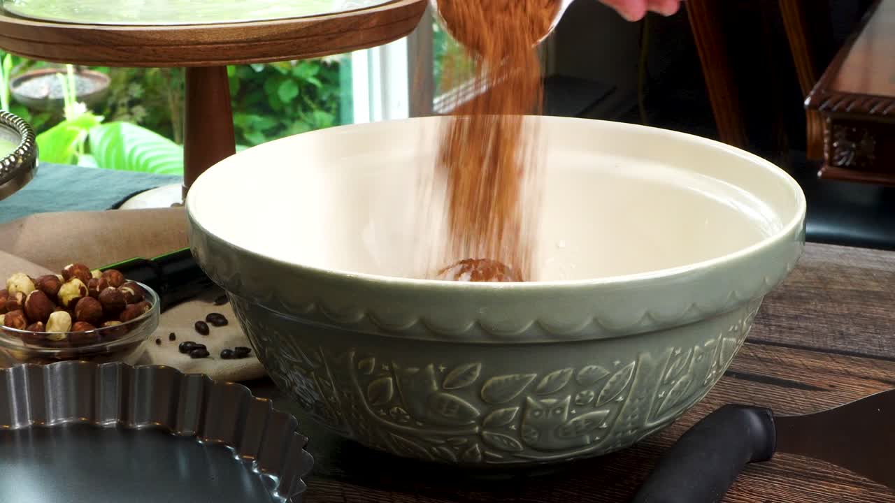 A delicious dessert, Coffee Hazelnut Cream Tart. Made with espresso powder, chocolate crust and loaded with crushed hazelnuts. Great with coffee. Adding ingredients into a large green mixing bowl