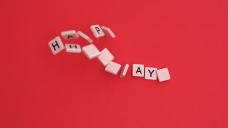 Letter-tiles-moving-to-spell-out-happy-holidays-on-red-background