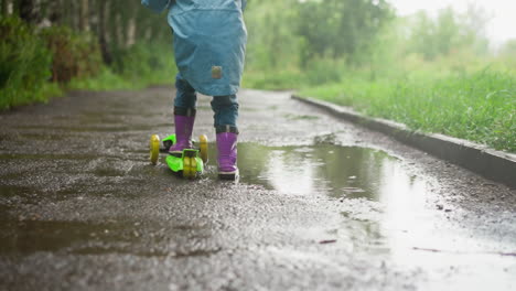 niño montando un scooter bajo la lluvia