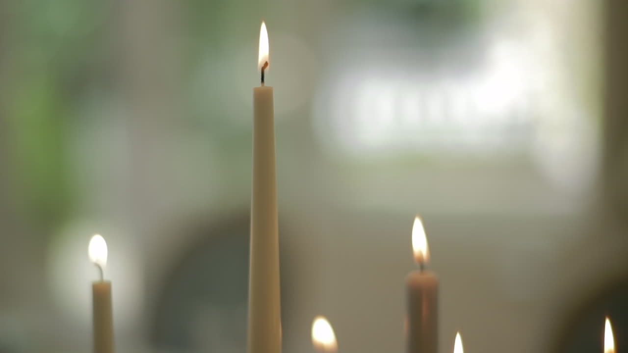 Cime di candele accese con rose bianche sullo sfondo