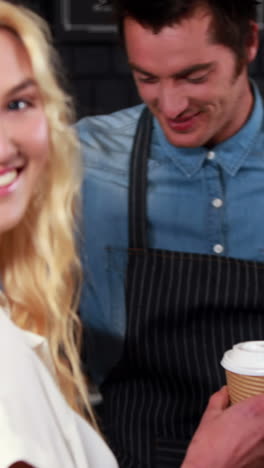 smiling waiter serving a coffee to a customer