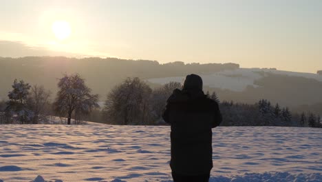 a photographer takes pictures of a beautiful sunset in a winterwonderland in upper austria