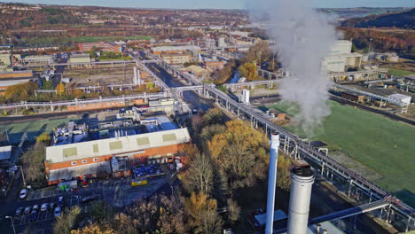 aerial footage moving towards a large industrial chemical plant, showing pipelines, metal structures, cooling towers and chemical storage