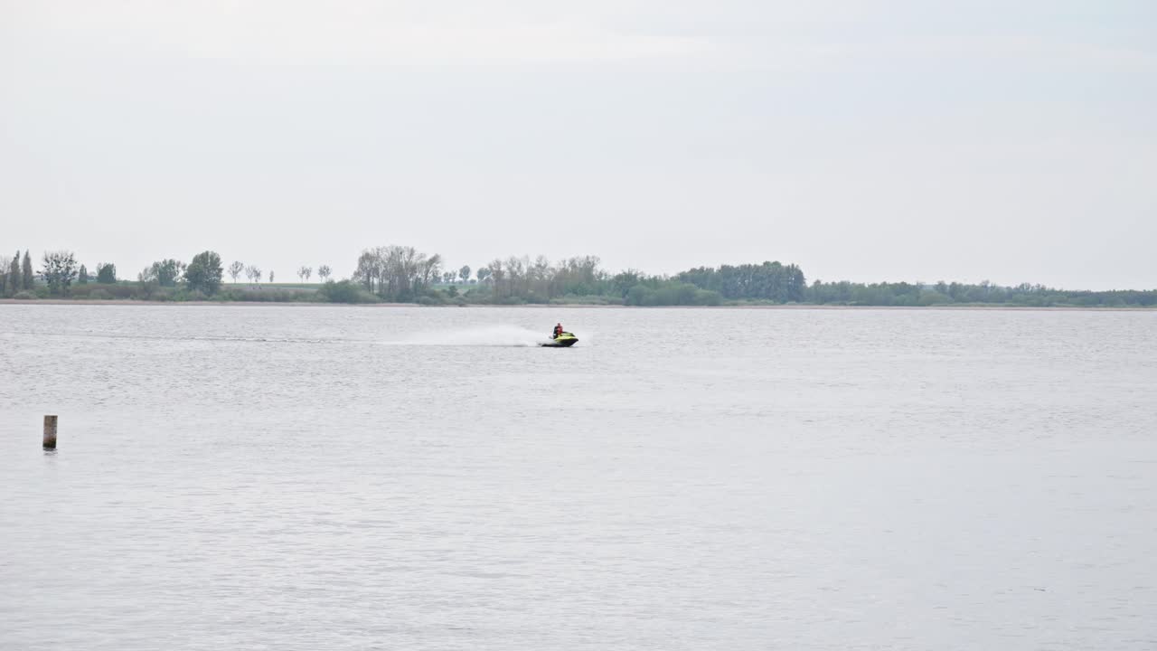 호수 를 가로질러 항해 하는 물 스쿠터, 그 뒤 에  물 의 스플래시 를 만들어 낸다 - 넓은 느린 동작 촬영