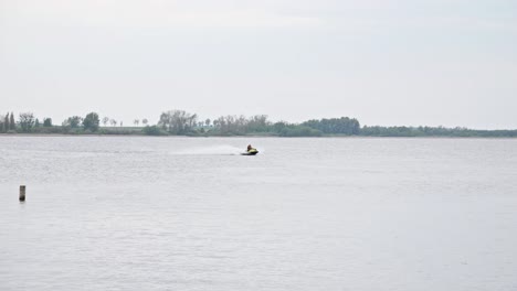 Una-Moto-Acuática-Navegando-Por-El-Lago,-Creando-Un-Chorro-De-Agua-Blanca-A-Su-Paso---Toma-Amplia-En-Cámara-Lenta