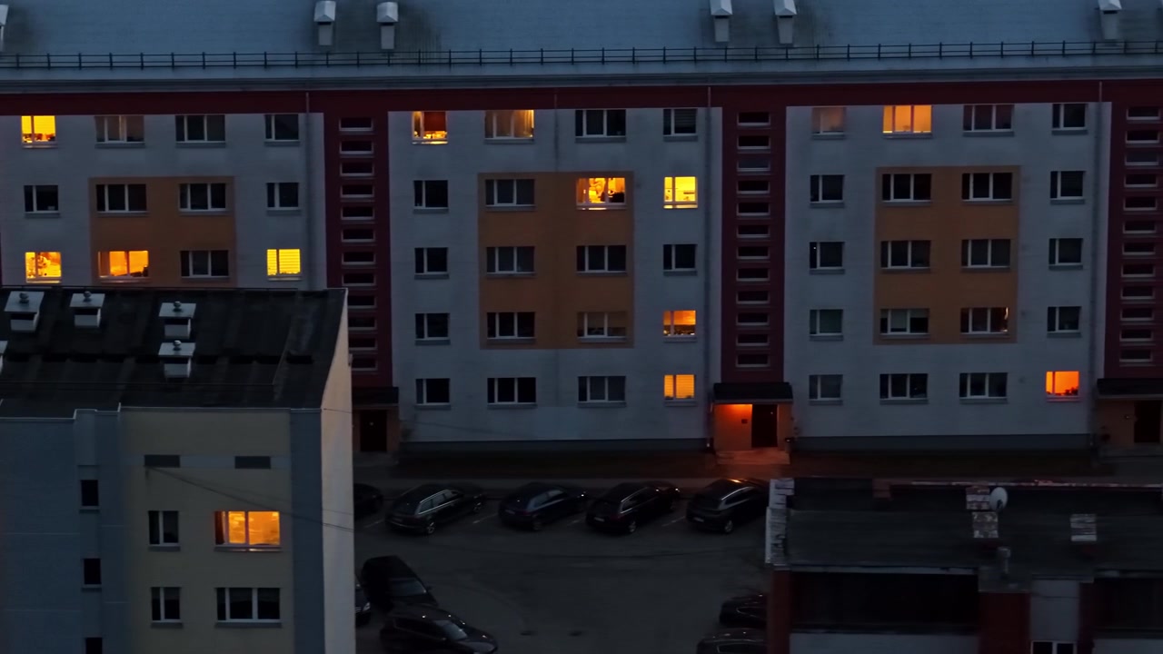 Evening aerial view of apartment building windows turning on and off in a residential district