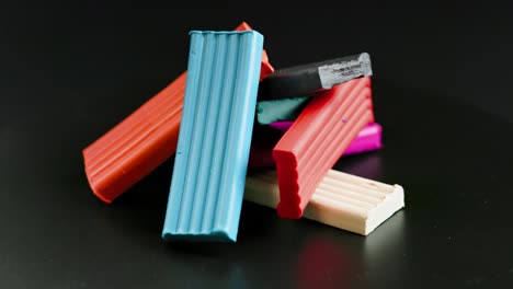 pequeña pila de piezas rectangulares de plastilina de color girando lentamente sobre un fondo negro