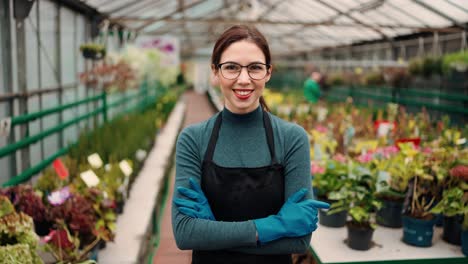 female worker florist crossing her arms standing on the greenhouse background