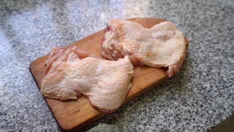 carne blanca cruda todavía con la piel en la tabla de cortar