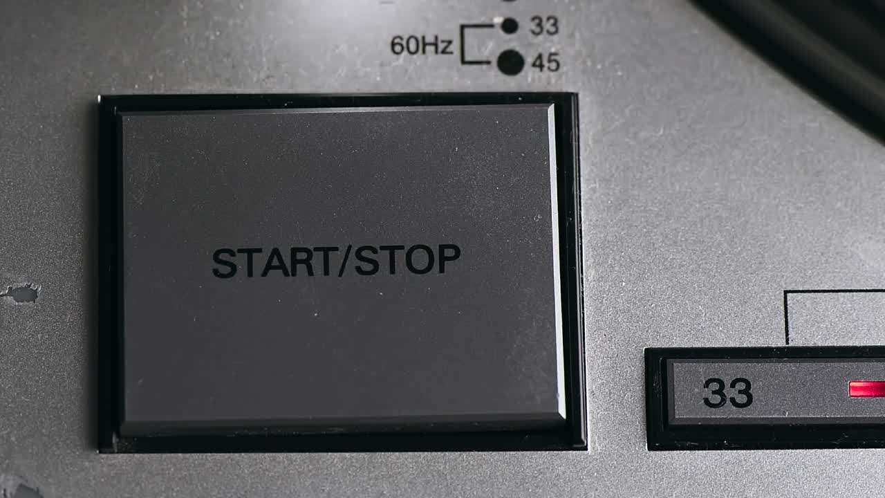 Pressing on button on vinyl player with turntable starting spinning