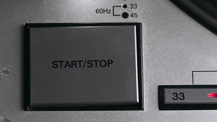 Pressing on button on vinyl player with turntable starting spinning